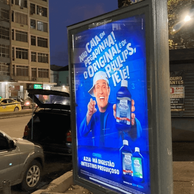 Placa em ponto de ônibus com imagem do humorista Sérgio Mallandro segurando o Leite de Magnésia de Phillips.